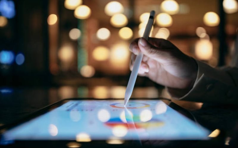 A businessperson is using a stylus to edit work reports on a tablet computer, which, combined with a mobile device, allows them to work more smoothly.